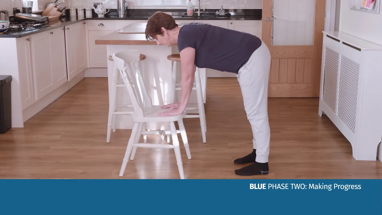 En kvinna som böjer sig över en stol